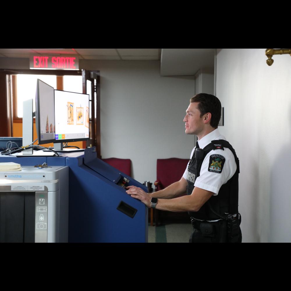 Protective Service Officer operating screening equipment