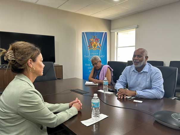 trois personnes assises autour d’une table dans une salle de réunion