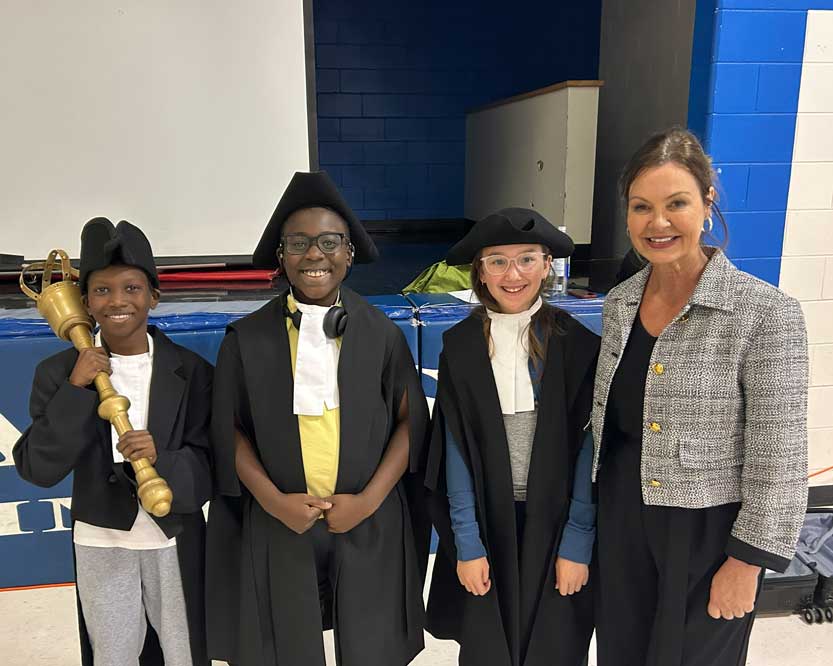 Trois enfants en costume de président aux côtés de la présidente de l’Assemblée.
