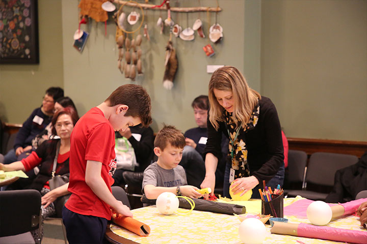 an adult and two children making crafts at a table