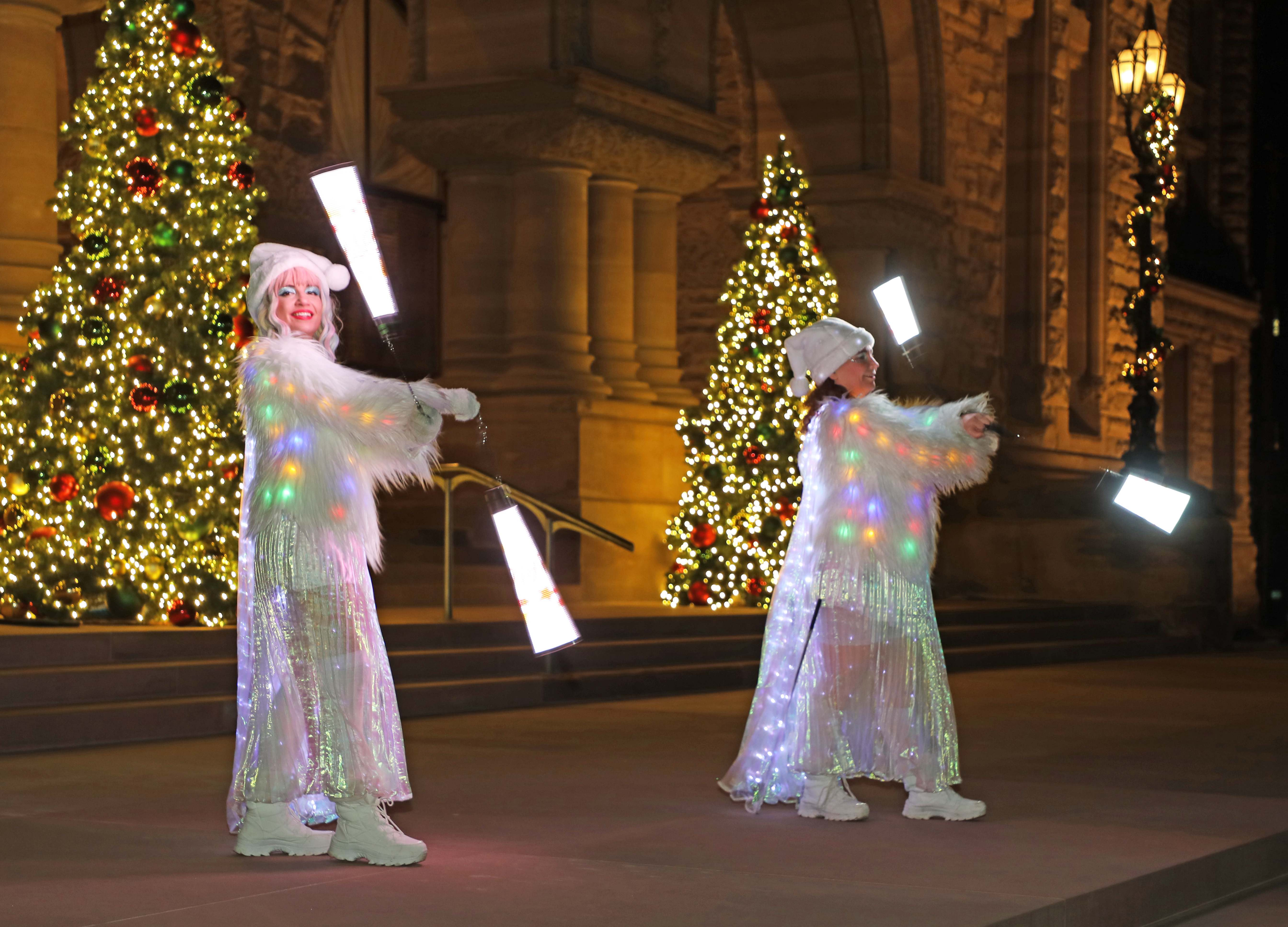 Deux femmes en pleine performance de jonglerie lumineuse devant l’édifice de l’Assemblée.