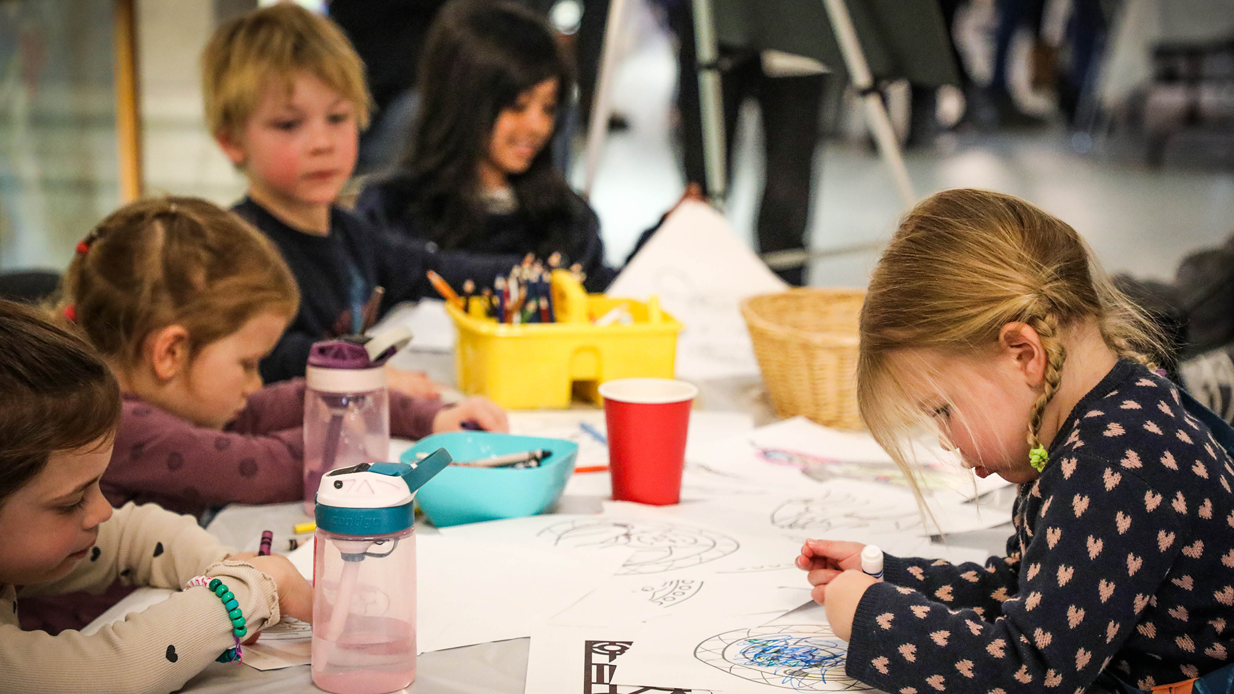 a group of children colouring and drawing at a table