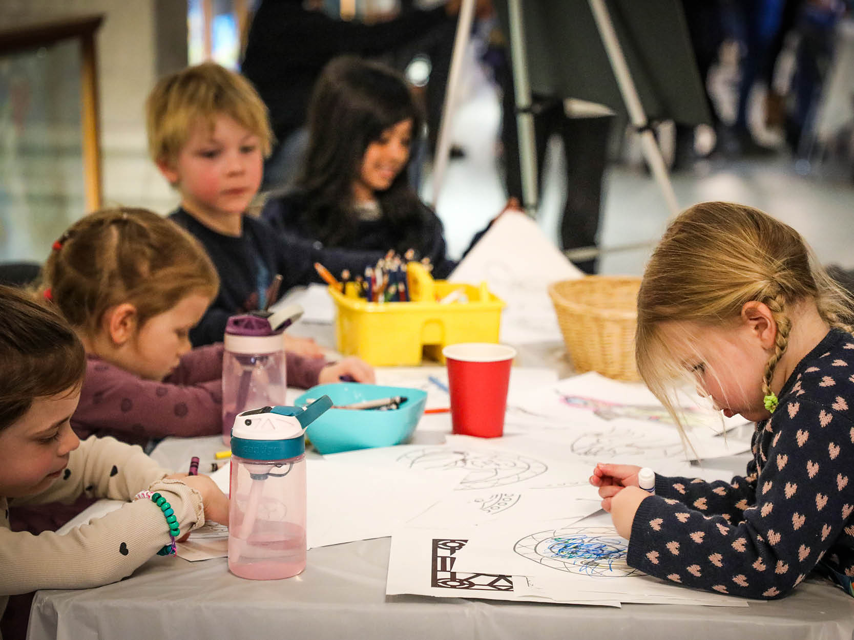 a group of children colouring and drawing at a table