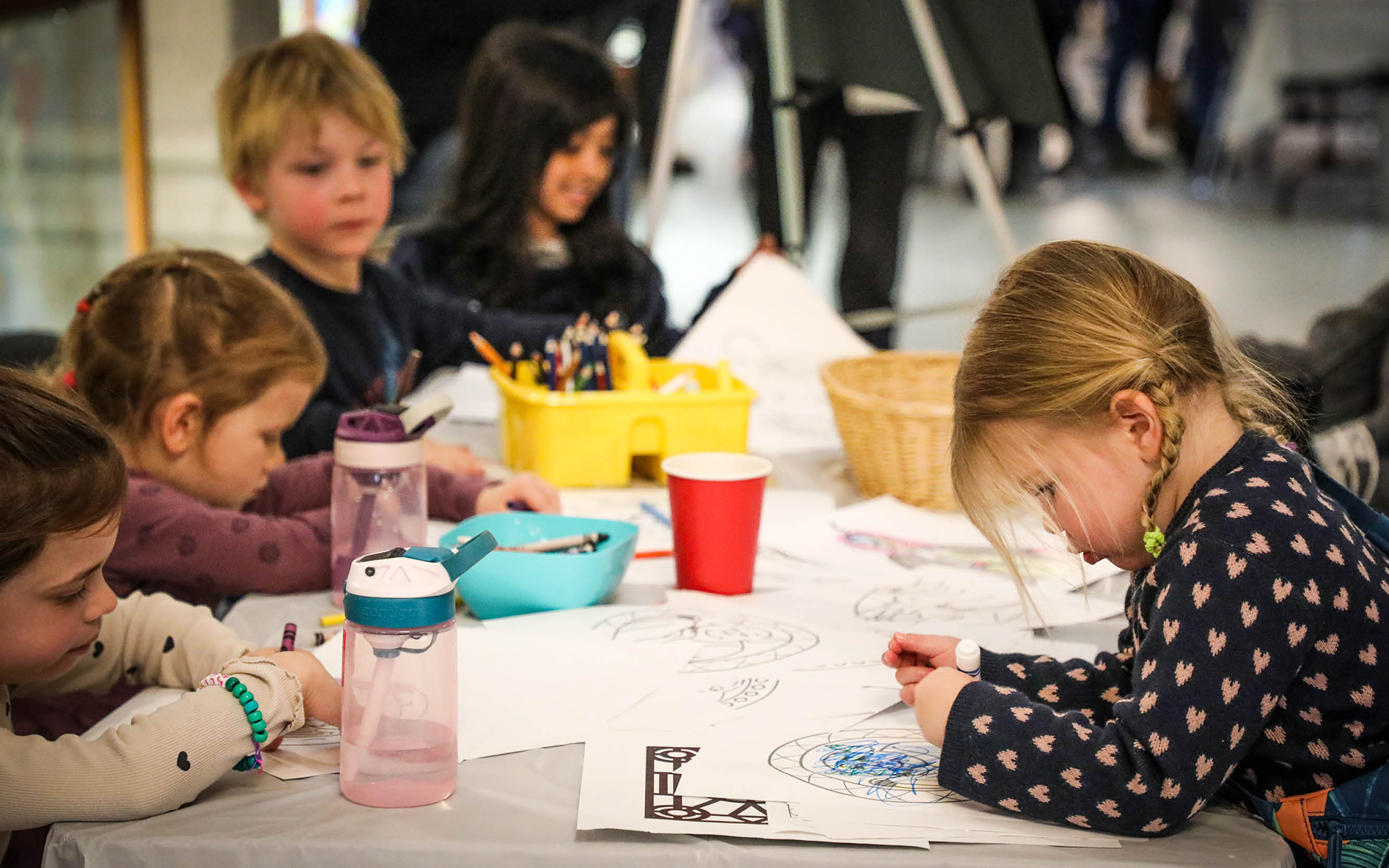 Un groupe d’enfants en train de dessiner et de colorier autour d’une table.