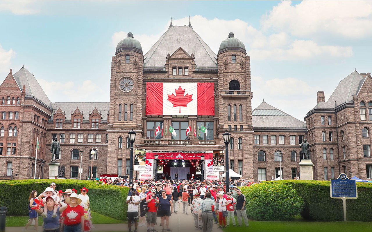 Des personnes marchent sous le soleil vers l’édifice de l’Assemblée législative pendant la Fête du Canada 2025