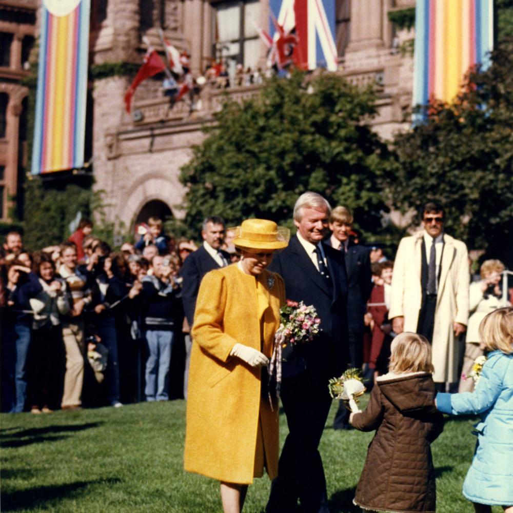 Sa Majesté la reine Elizabeth II accepte des fleurs de la part de quelques jeunes admiratrices pendant la visite royale à Queen's Park en 1984.