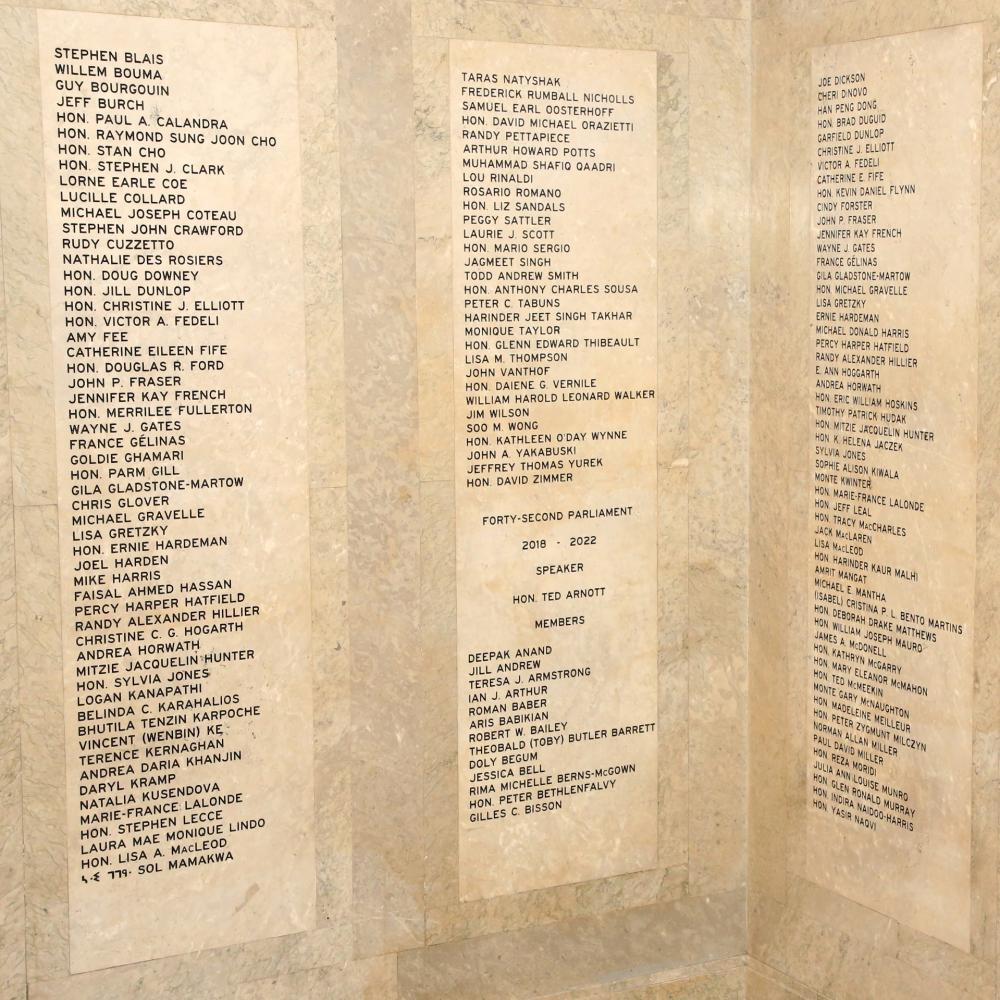 Photo montrant les murs de marbre portant les noms des anciens députées et députés.